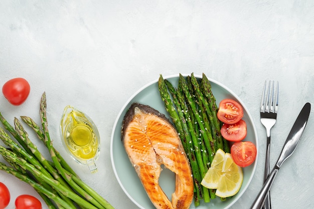 Grilled salmon steak and asparagus with ingredients on grey background Top view copy space