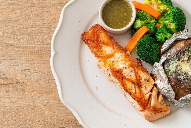 Photo grilled salmon steak with bake potato and vegetables