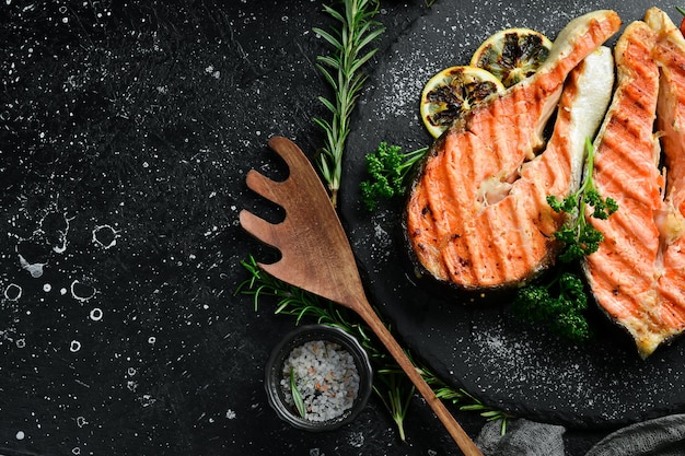 Grilled salmon steak with spices and vegetables On a black background Photo for the menu