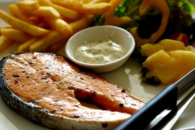 Grilled salmon steak with tarragon sauce salad and french fries