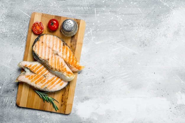 Photo grilled salmon steaks with tomatoes and a sprig of rosemary