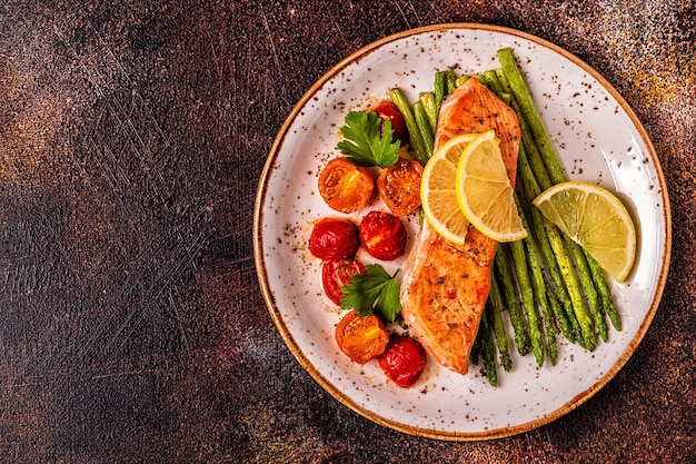 Foto salmone alla griglia con asparagi e pomodori, vista dall'alto.