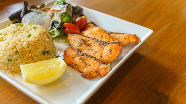 Salmone alla griglia con riso fritto, insalata mista e limone