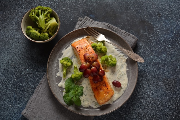 Grilled salmon with roasted red grapes and broccoli in creamy garlic sauce