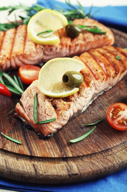 Grilled salmon with spices on cutting board on wooden background