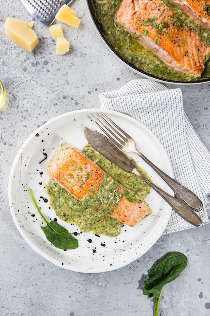 Grilled Salmon with spinach and garlic cream sauce on a plate, top view