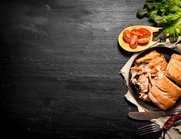 Salmone alla griglia con pomodori ed erbe aromatiche. sulla lavagna nera.