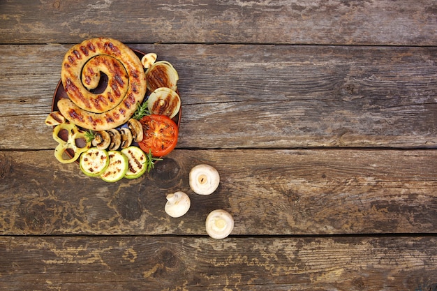 焼きソーセージと野菜の古い木製の背景。上面図。フラット横たわっていた。