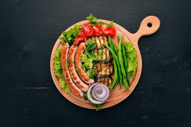 Salsiccia alla griglia con fagioli di melanzane e pomodori sulla tavola cibo sano su un tavolo di legno nero vista dall'alto spazio libero per il testo