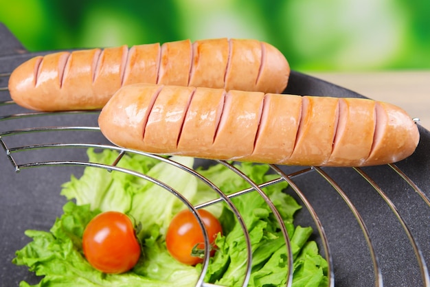 Grilled sausage in wok on bright background