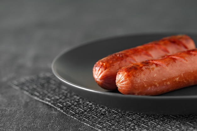 Photo grilled sausages on gray plate dark background selective focus