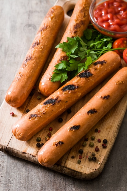 Grilled sausages and ketchup on wooden table