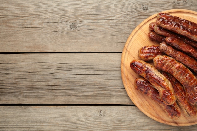 Grilled sausages on plate on grey wooden surface with copy space