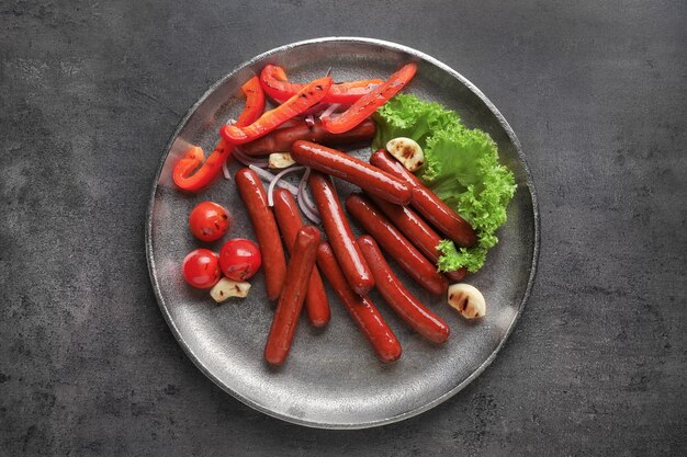 Grilled sausages served with vegetables on metal plate