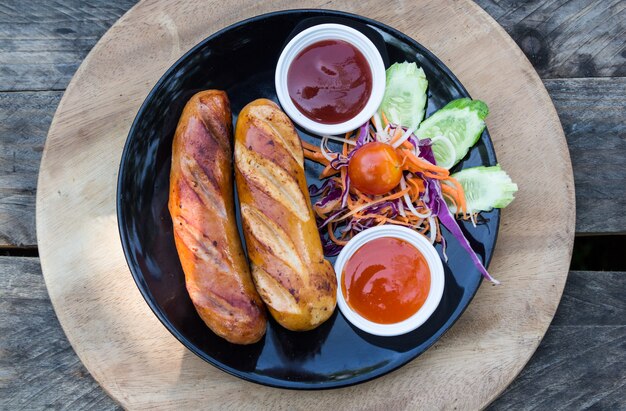 grilled sausages and vegetables with in black dish