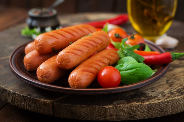 Grilled sausages and vegetables on a wooden table in rustic style.