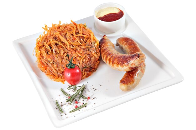 Grilled Sausages with garnish of braised cabbage and sauce on square serving plate, isolated on white background.