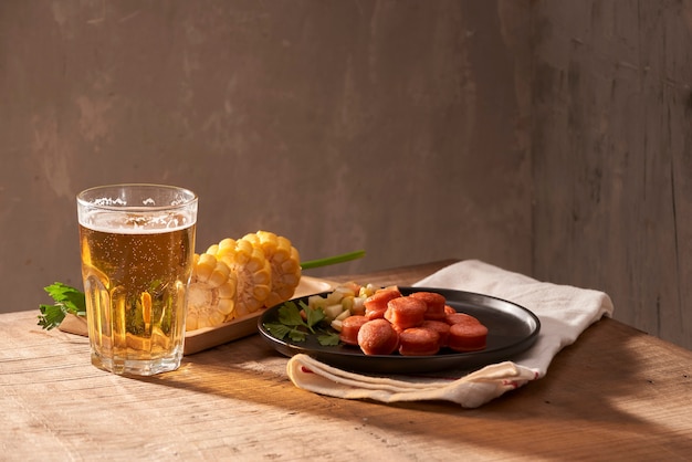 コピースペースのある木製のテーブルにビールのグラスとソーセージのグリル。