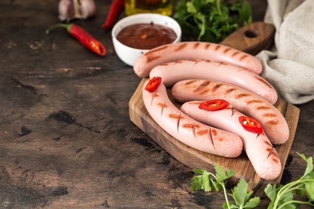 Photo grilled sausages with ketchup, herbs and chili peppers