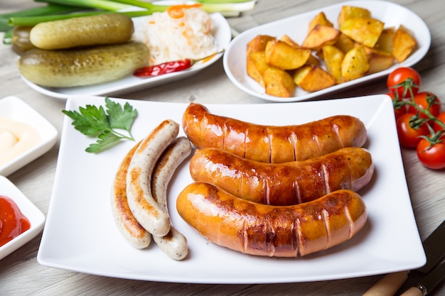 Grilled sausages with potatoes, cucumbers and sauerkraut, with two sauces.