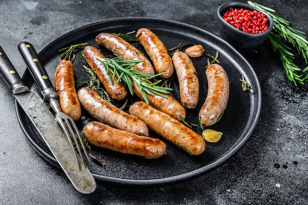 Grilled sausages with rosemary herbs, beef and pork meat. Black background. Top view.