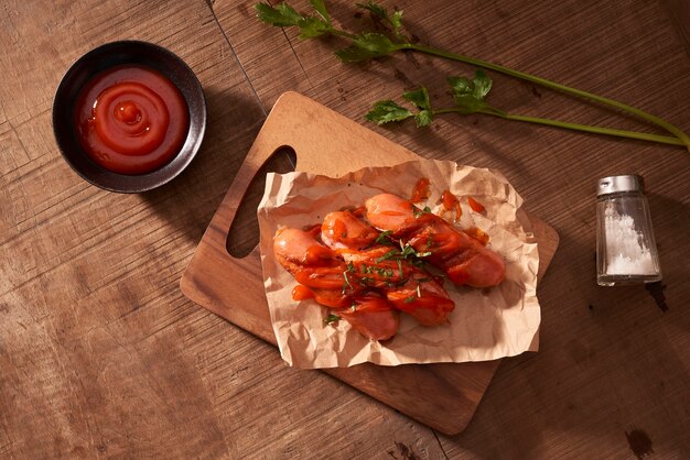 Salsicce alla griglia con salsa ketchup su un tavolo di legno