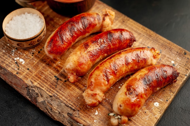 Grilled sausages with spices, ketchup and rosemary on a stone table, ready to eat