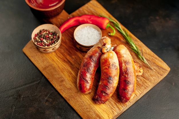 Grilled sausages with spices, ketchup and rosemary on a stone table, ready to eat