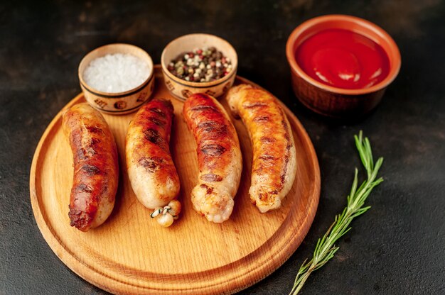 Grilled sausages with spices, ketchup and rosemary on a stone table, ready to eat