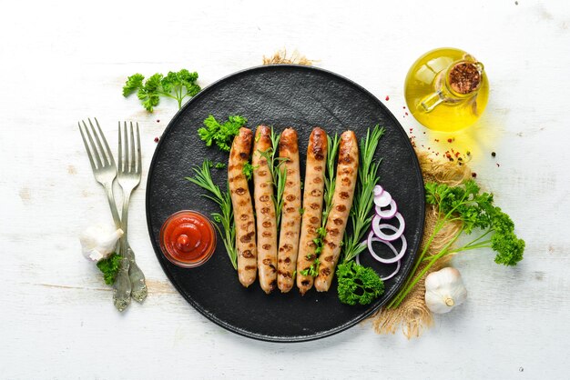 Grilled sausages with tomato sauce on a black stone plate BBQ Top view Free copy space