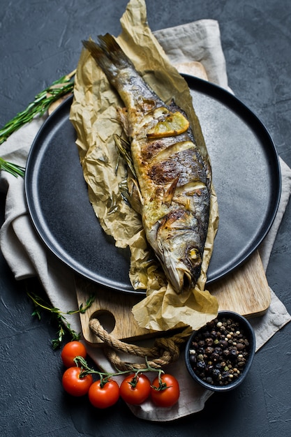 Grilled sea bass on Kraft paper in a black plate. 