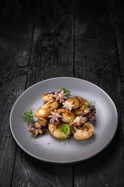 grilled seafood in a gray round plate on a dark wooden table