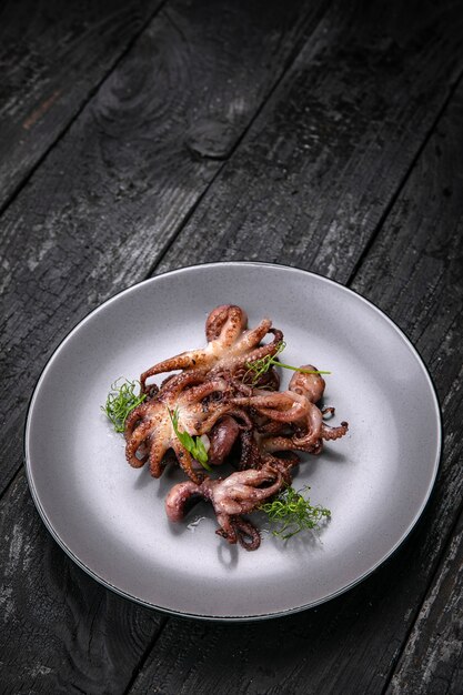 grilled seafood in a gray round plate on a dark wooden table