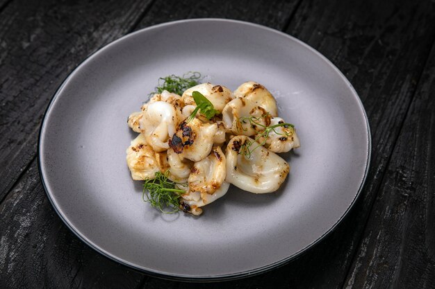 grilled seafood in a gray round plate on a dark wooden table