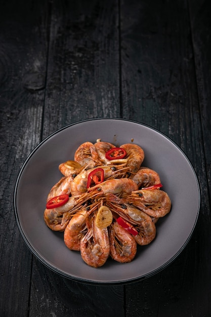 grilled seafood in a gray round plate on a dark wooden table