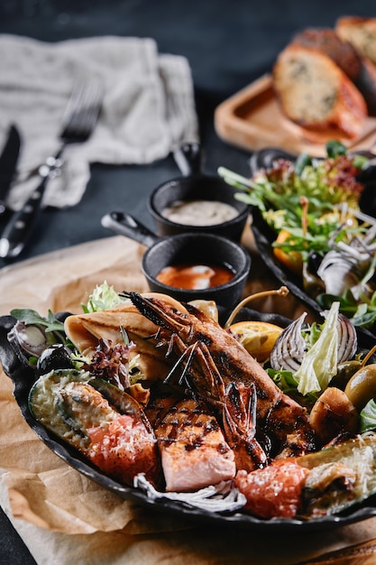 Photo grilled seafood platter. assorted delicious grilled seafood with vegetables. grilled mixed bastards with pepper sauce and vegetables. blue background