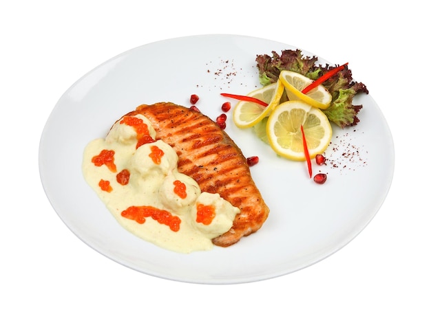 Жареный лосось из морепродуктов с икрой, красным перцем и лимоном на белой круглой тарелке