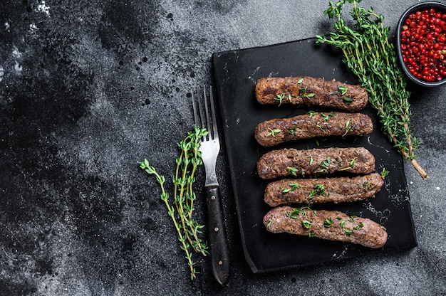 Grilled Shish kebab meat  sausages. Black background. Top view. Copy space.