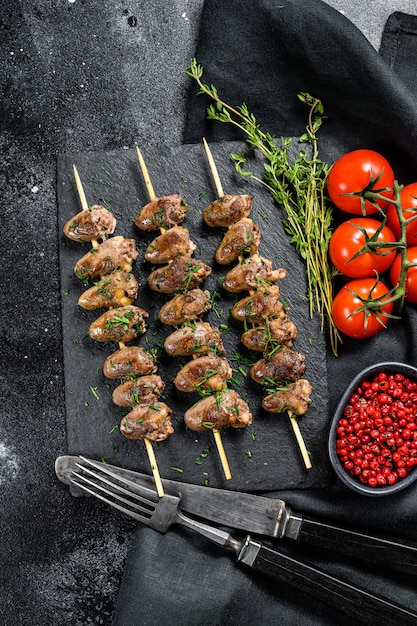 Grilled shish kebab with chicken hearts. Black background. Top view.