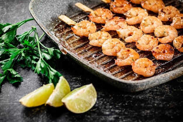 Grilled shrimp in a frying pan with parsley and pieces of lime