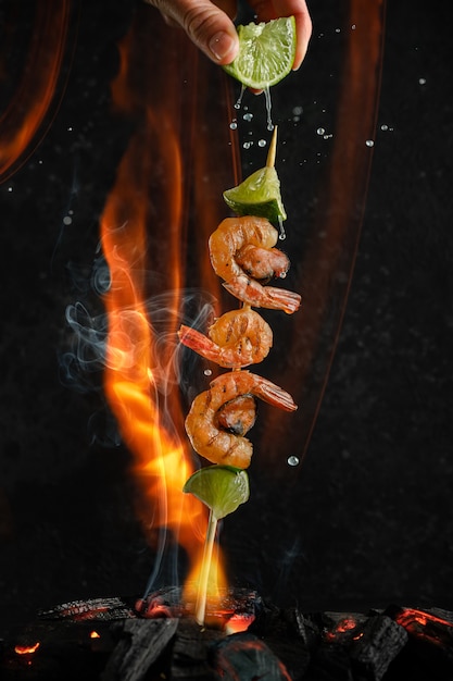 Grilled shrimp and mussel skewers over coal heat on fire and smoke background