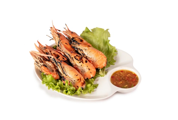 Grilled shrimp on a plate served with spicy sauce over white background