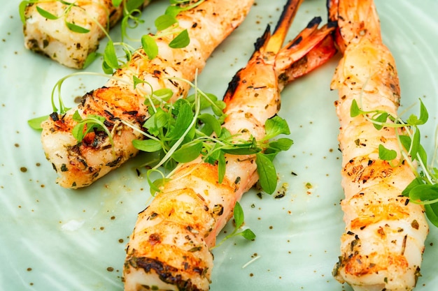 Grilled shrimp on a plate with herbs on the side.