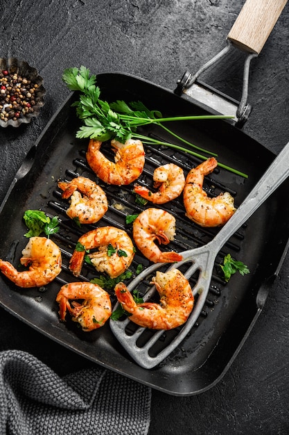 Photo grilled shrimps on pan on dark