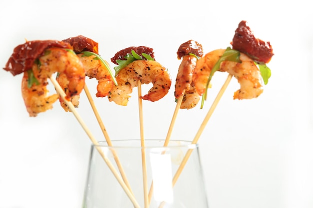 Photo grilled shrimps with the dried tomato and arugula on sticks a canape stand in a glass