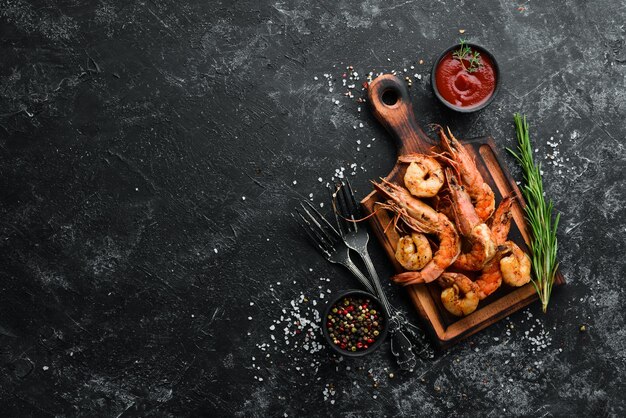 Grilled shrimps with sauce on black stone background Top view Free copy space