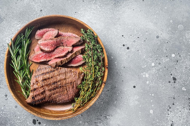 Grilled sliced Skirt Steak on a plate with herbs Gray background Top view Copy space