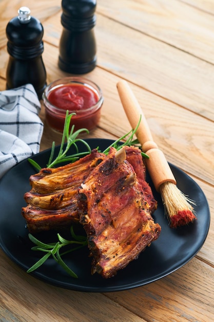 Grilled and smoked pork ribs with barbeque sauce on an old\
vintage wooden cutting board on old wooden table background tasty\
snack to beer american food concept top view