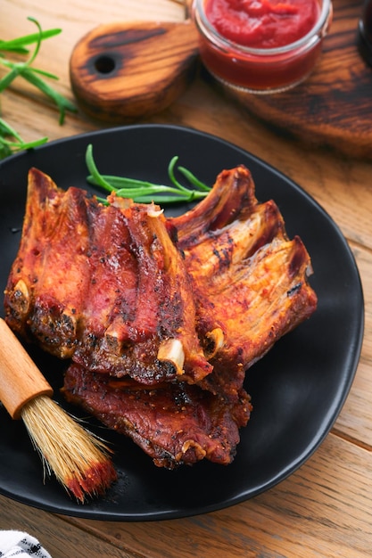 Grilled and smoked pork ribs with barbeque sauce on an old
vintage wooden cutting board on old wooden table background tasty
snack to beer american food concept top view