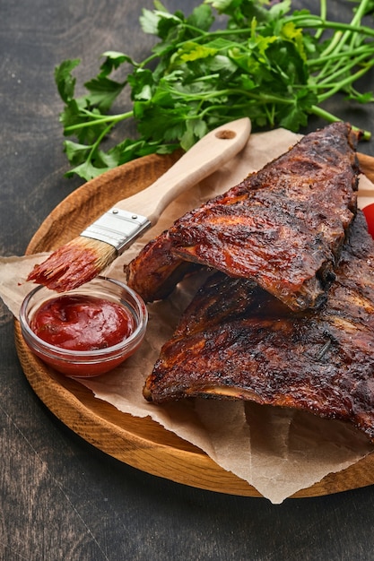 Grilled and smoked pork ribs with barbeque sauce on an old vintage wooden cutting board. Tasty snack to beer. Closeup image.